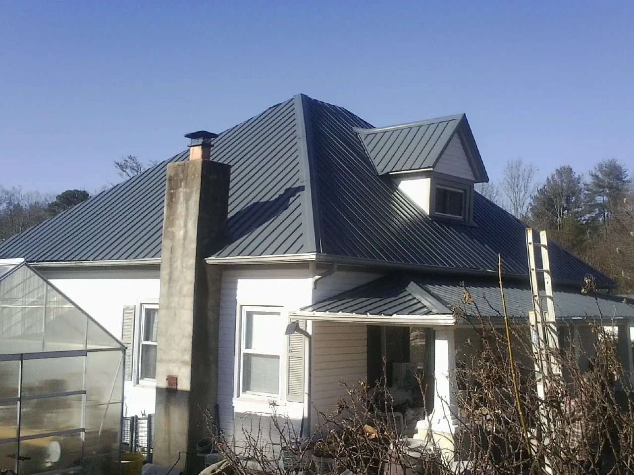 Dark blue standing seam metal roof on a white farmhouse with dormer — Slate & Tile Roof Repair by Roofing Brothers in Roseville