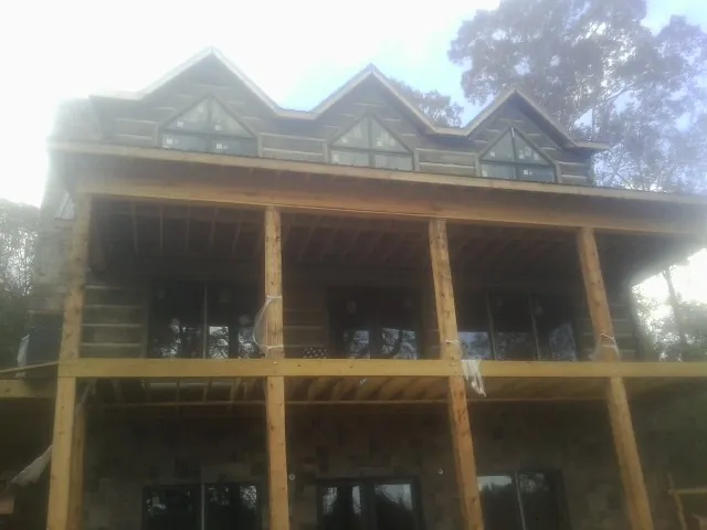 Dormers and porch framing on a large log home under construction — Roof Coating work by our crew in Roseville